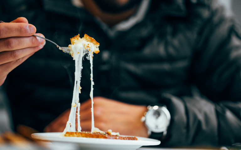 person with fork and bite of cheesy foods to understand hunger